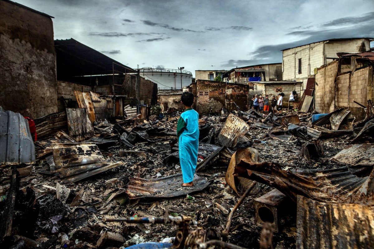 TOPSHOT - A boy stands in the remains of a burnt house in a residential area in Plumpang, north Jakarta on March 4, 2023, after a fire at a nearby state-run fuel storage depot run by energy firm Pertamina. (Photo by ADITYA AJI / AFP)